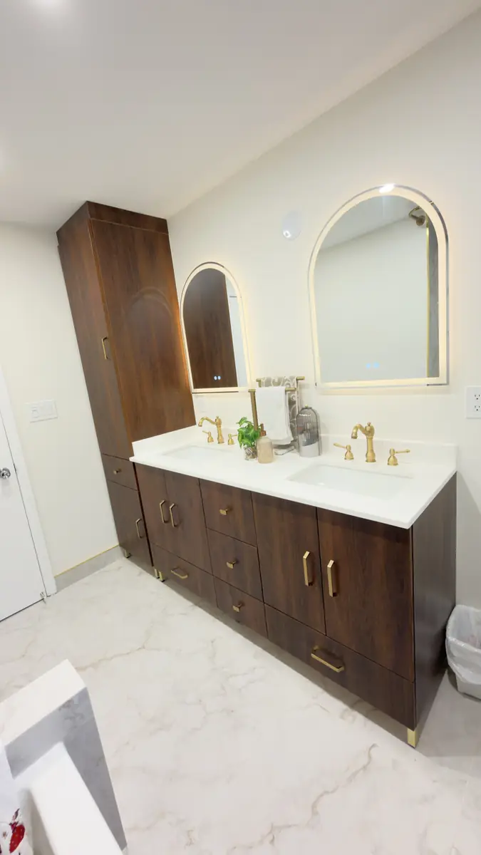 Walnut double vanity with gold hardware, quartz top and a floor-to-ceiling linen tower