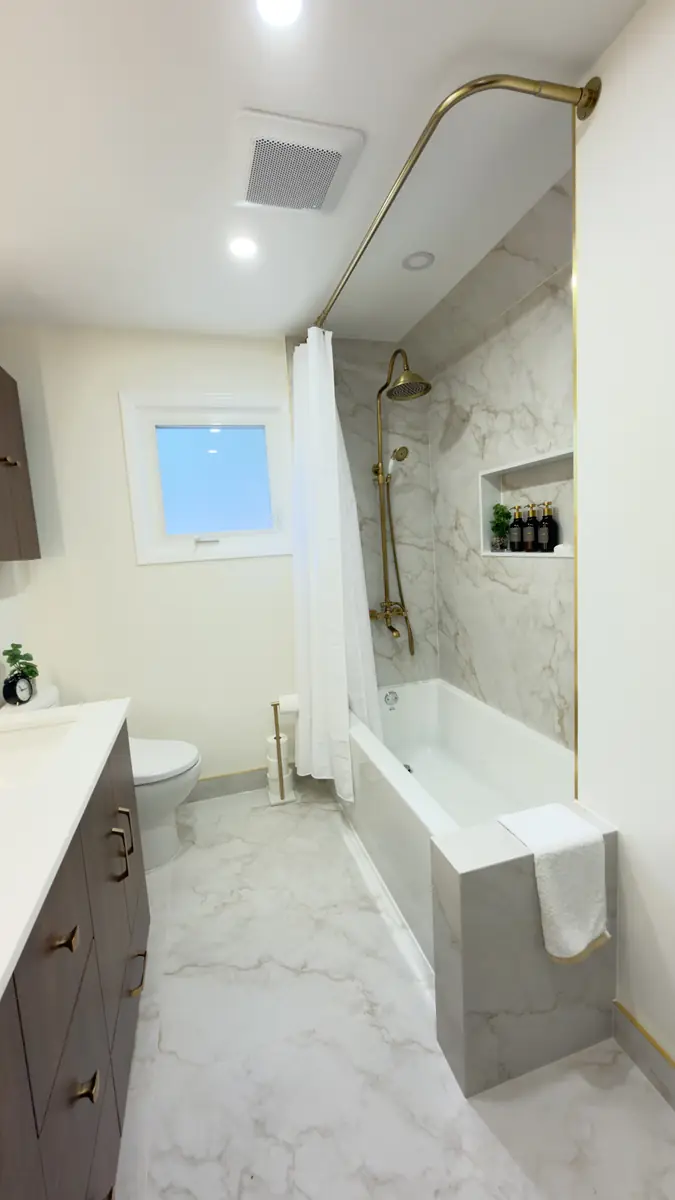 Tub and shower with a marble-look surround, recessed niche and brushed gold fixtures