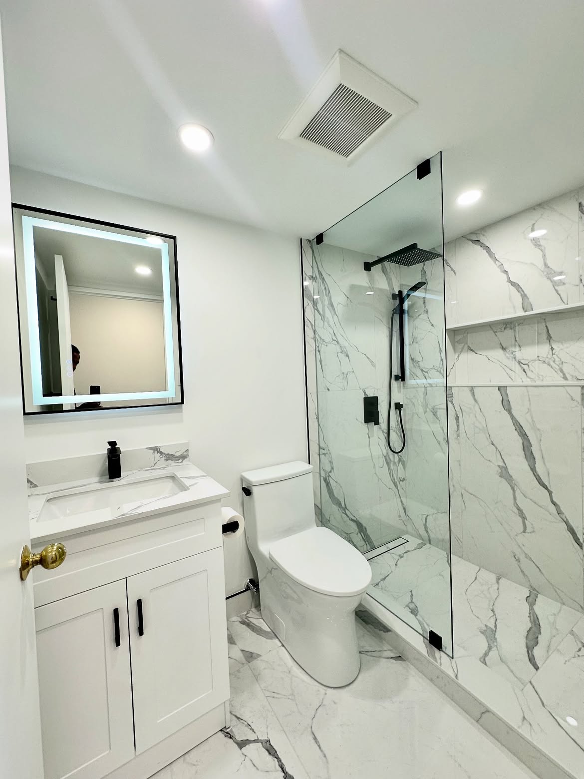 Dated pink bathroom replaced with white marble tile and a walk-in shower — after