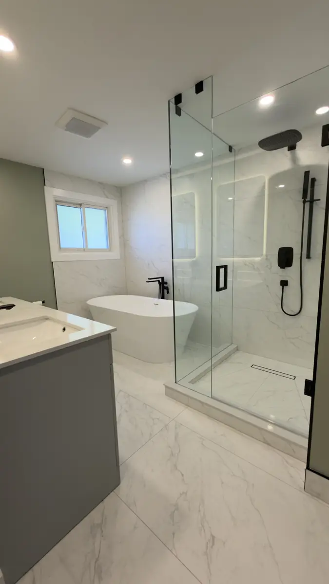 Primary ensuite with sage walls, a freestanding tub, marble-look tile and a glass walk-in shower